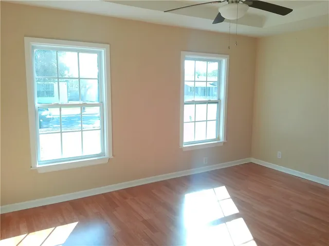an empty room with wooden floor and windows