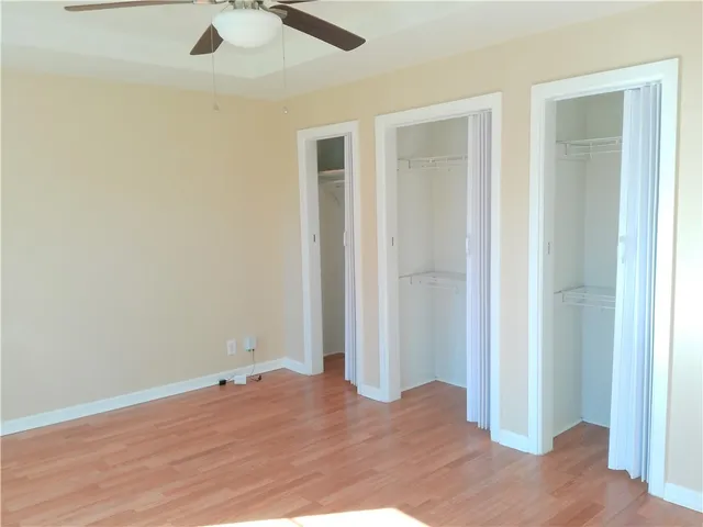 an empty room with wooden floor closet and windows