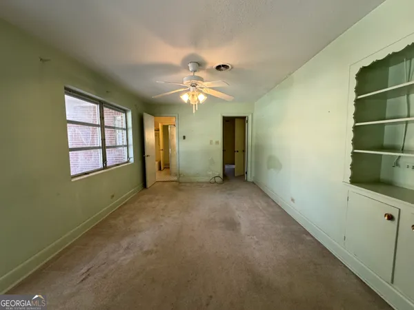 a view of a room with a ceiling fan and window
