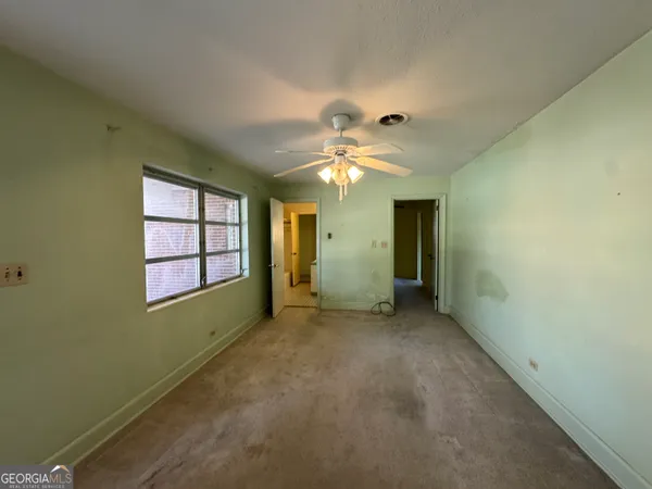 an empty room with windows and fan chandelier