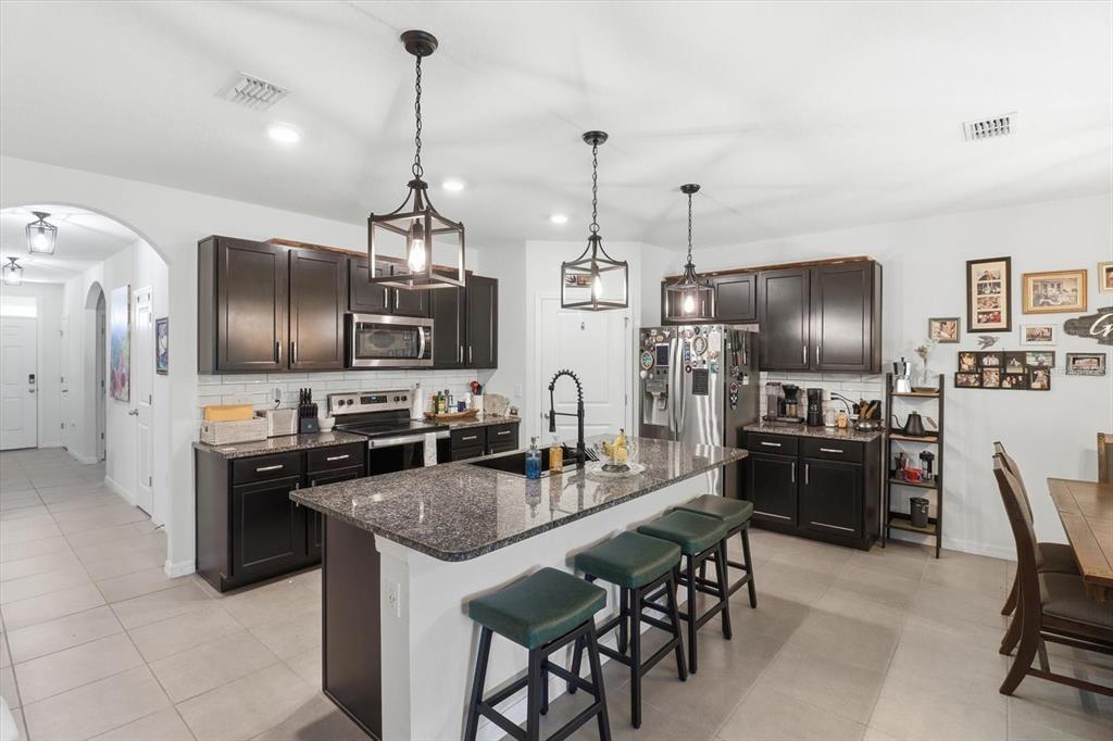 660 Hickory Course Loop Ocala, FL 34472 - Photo 8 of 45 a kitchen with stainless steel appliances granite countertop a stove top oven a sink dishwasher a dining table and chairs with wooden floor