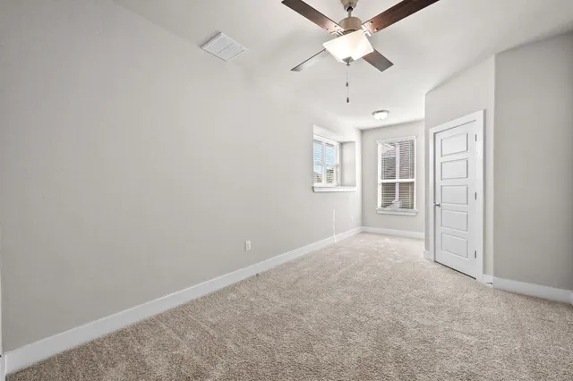 an empty room with windows and fan