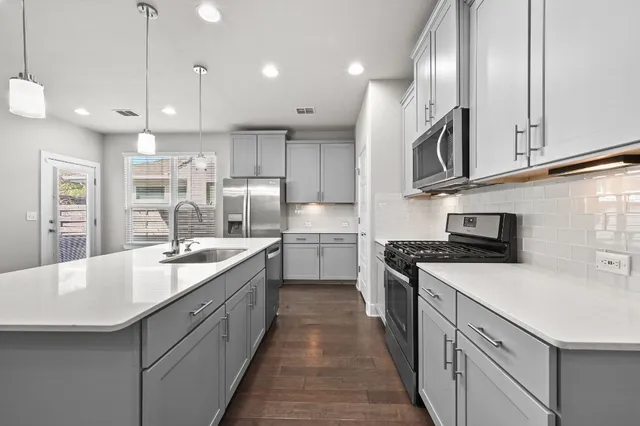 a kitchen with stainless steel appliances granite countertop a sink a stove and a refrigerator