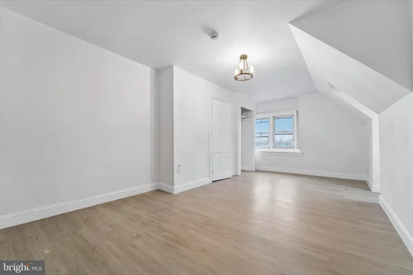 an empty room with wooden floor chandelier and windows