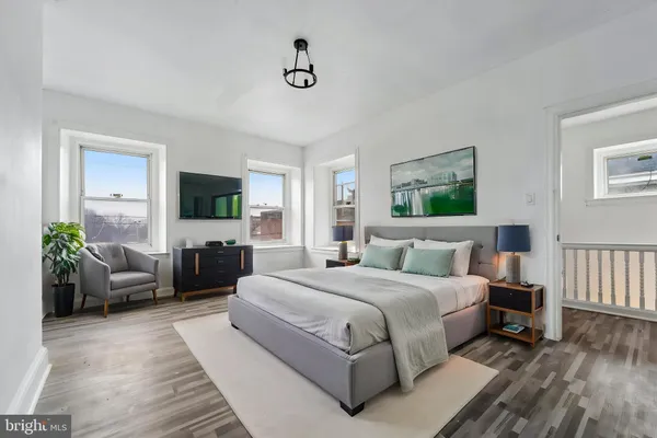 a bedroom with a large bed couch and windows