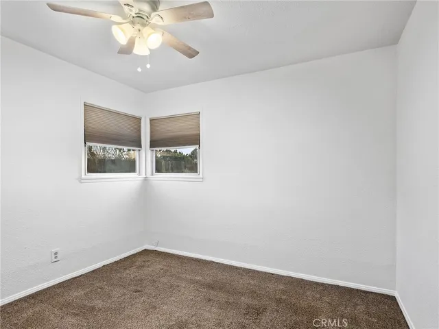 an empty room with a chandelier fan and closet area