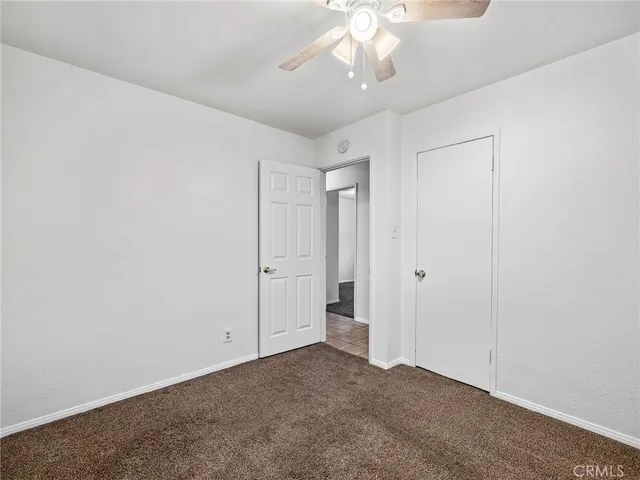 an empty room with a chandelier fan and windows