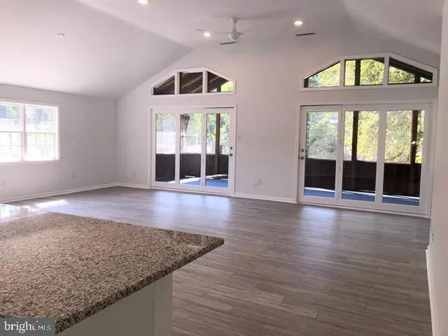 an empty room with wooden floor fan and windows