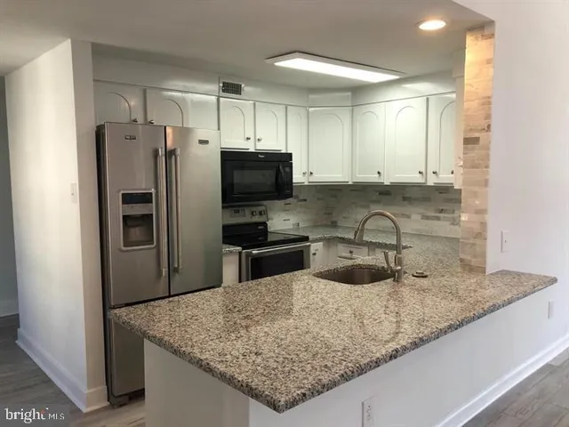 a kitchen with stainless steel appliances granite countertop a sink a refrigerator and a granite counter tops