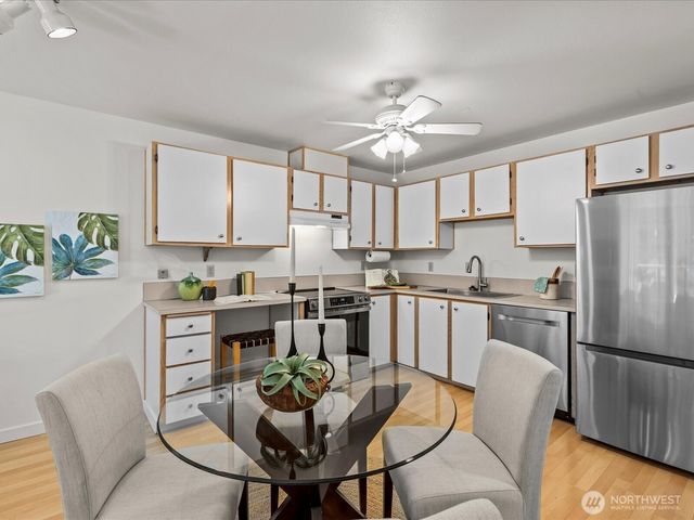 a kitchen with stainless steel appliances granite countertop a dining table chairs refrigerator and microwave
