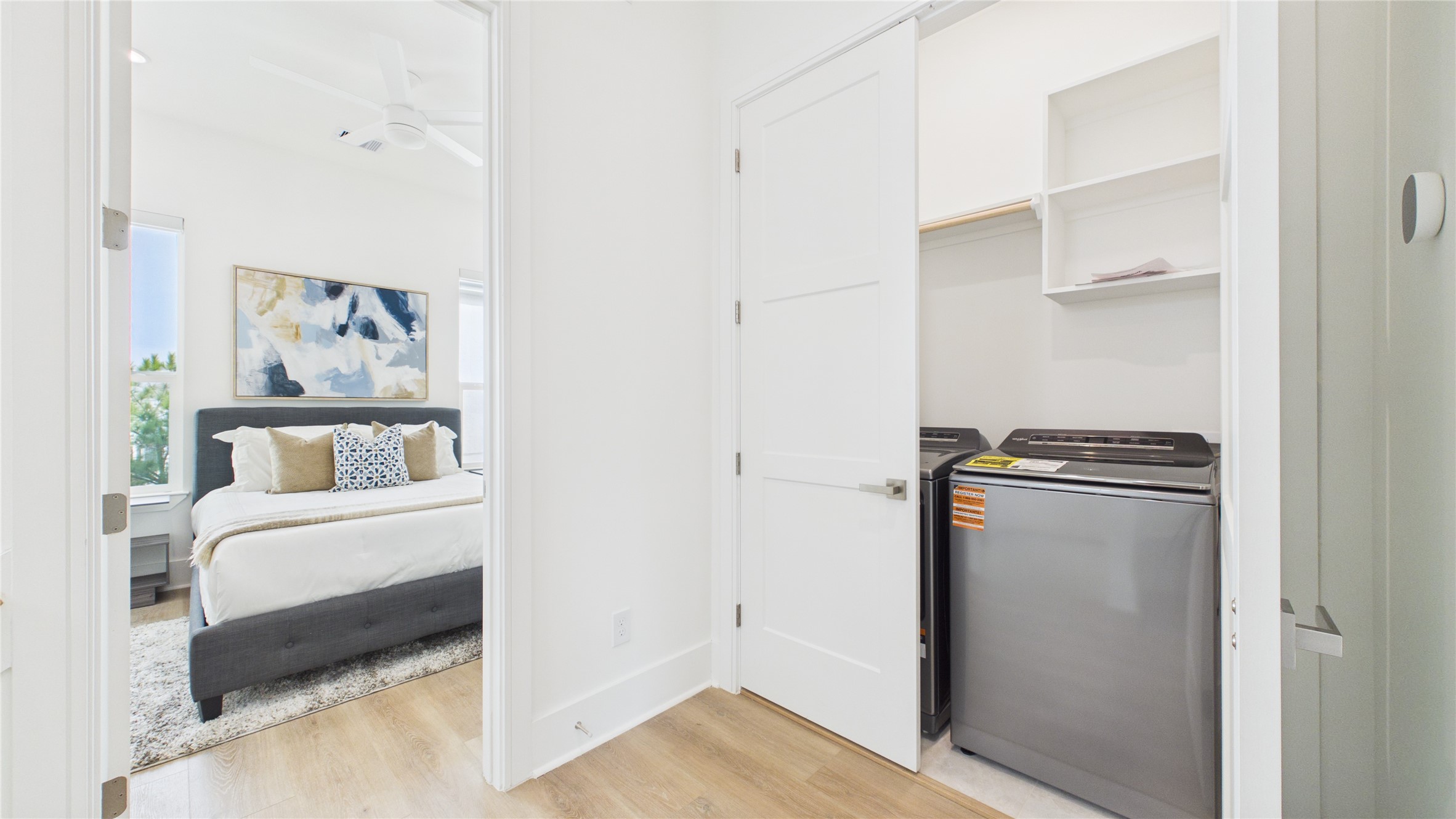 602 Skyland Terrace Way Houston, TX 77009 - Photo 21 of 40 This photo shows a bright, modern bedroom with a comfortable bed, adjacent to a laundry area with a washer and dryer neatly tucked into a closet space.