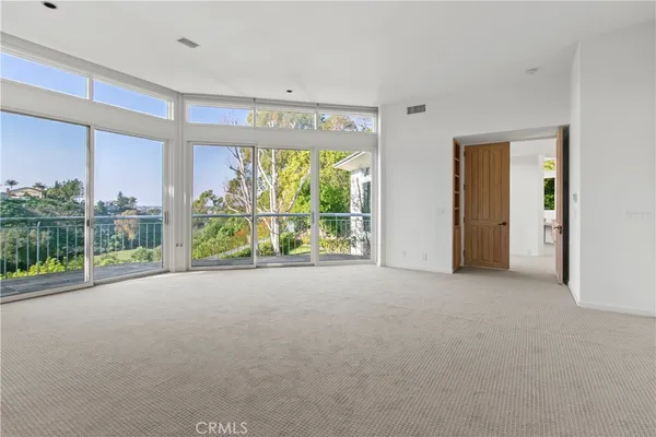 a view of a room with large windows and plants