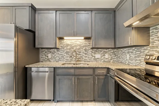 a kitchen with stainless steel appliances granite countertop a sink stove and cabinets