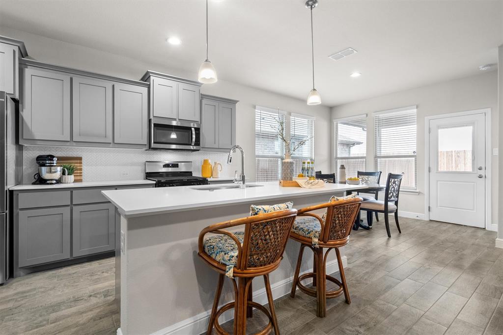 1864 Mensa Drive Haslet, TX 76052 - Photo 15 of 40 a kitchen with stainless steel appliances granite countertop a table chairs sink and cabinets
