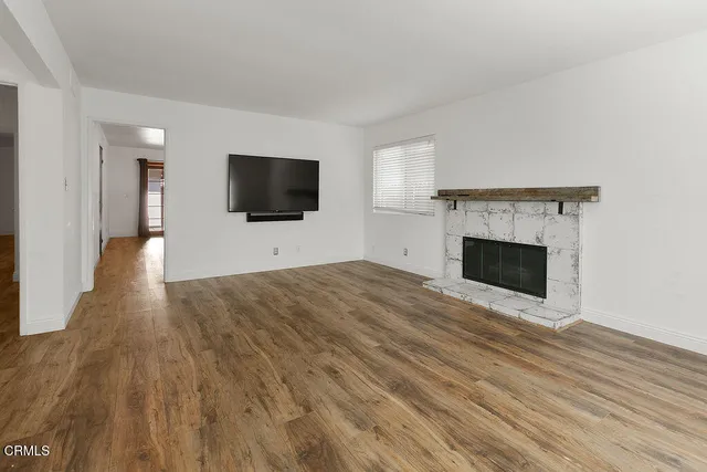 a view of a livingroom with an empty space & wooden floor and windows
