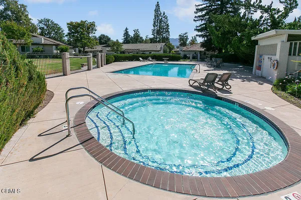 a view of swimming pool with outdoor seating and house in the background