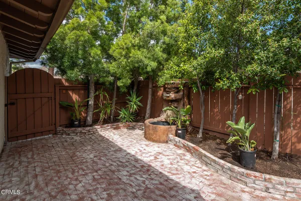 a view of a backyard with table and chairs potted plants and large tree