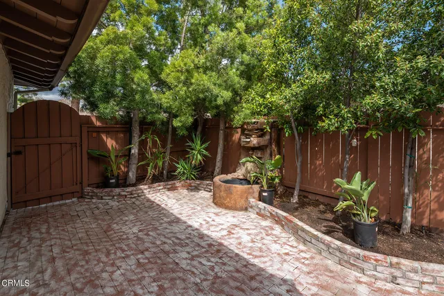 a view of a backyard with table and chairs potted plants and large tree