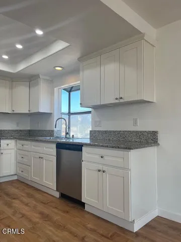 a kitchen with granite countertop white cabinets and a sink
