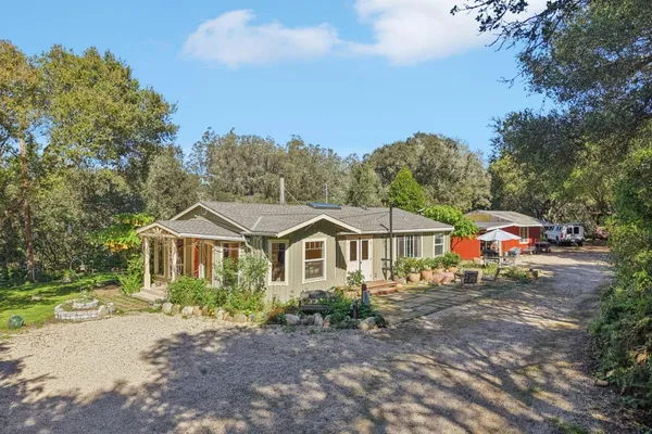 a view of a house with backyard and trees in the background
