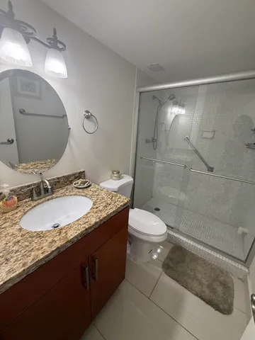 a bathroom with a granite countertop sink toilet and shower