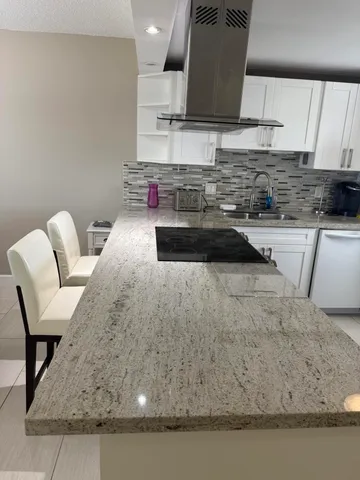 a kitchen with granite countertop a sink a stove and a wooden cabinets