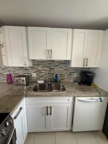 a kitchen with stainless steel appliances granite countertop a sink stove and white cabinets