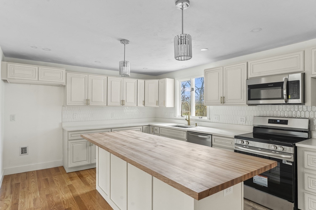 32 Laurel Lane Raynham, MA 02767 - Photo 6 of 30 a kitchen with a stove a sink and a refrigerator