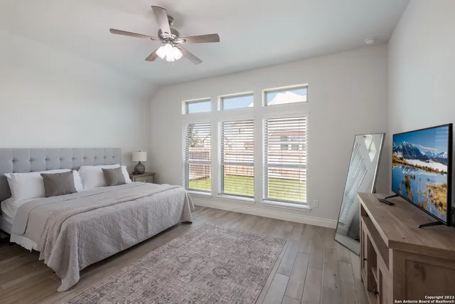 a bedroom with a bed a fireplace and a flat tv screen on a dresser