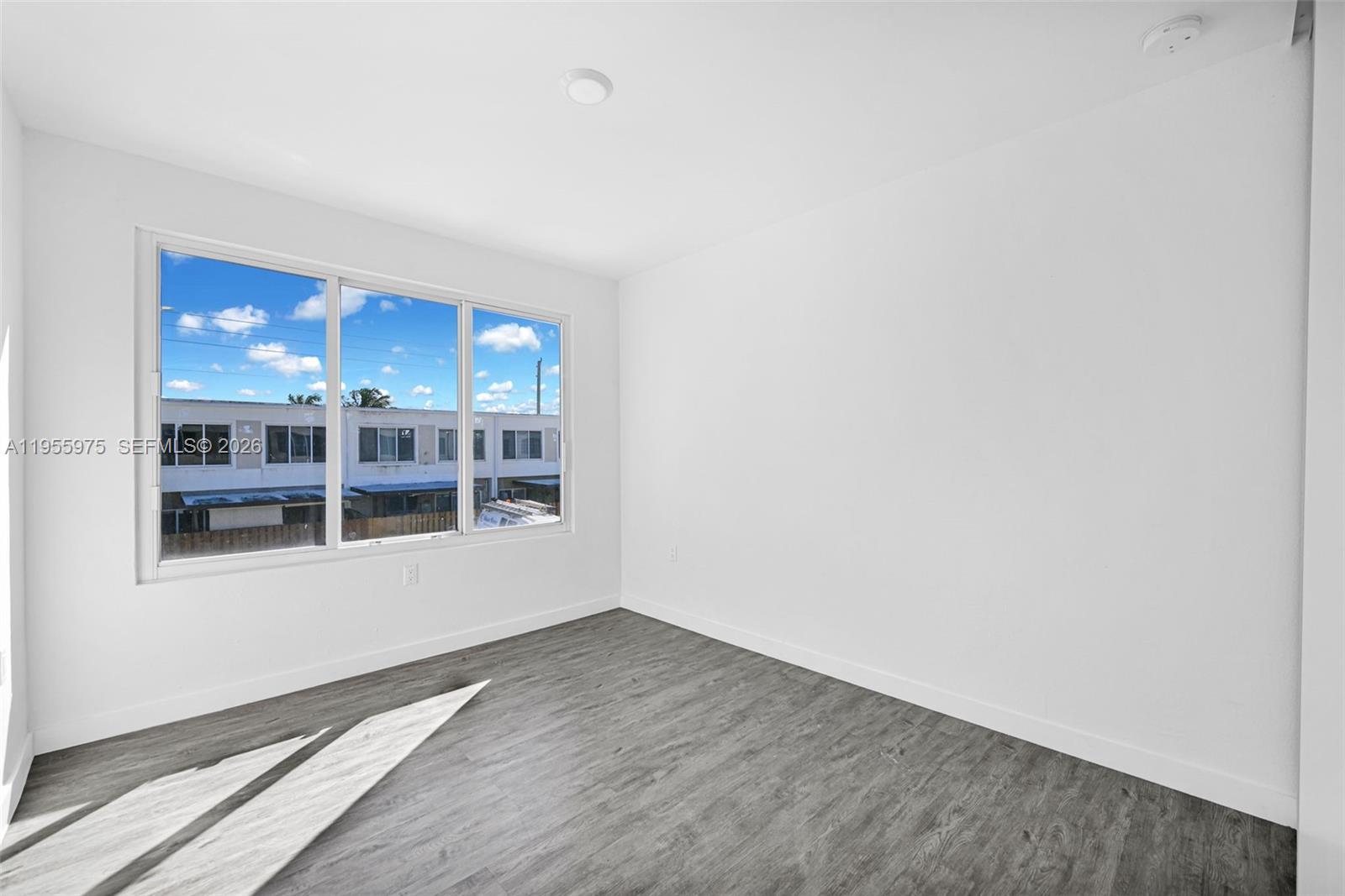 25874 Southwest 139th Court Homestead, FL 33033 - Photo 21 of 56 an empty room with wooden floor and windows