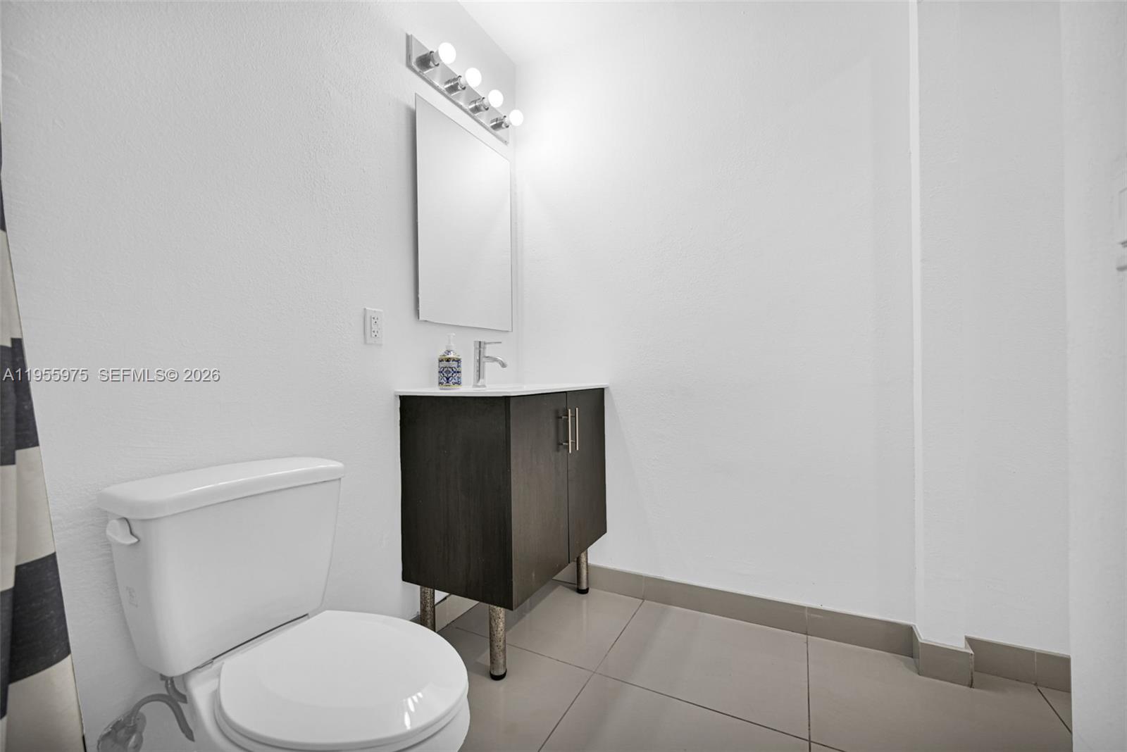 25874 Southwest 139th Court Homestead, FL 33033 - Photo 45 of 56 a white toilet sitting next to a bathroom sink and vanity