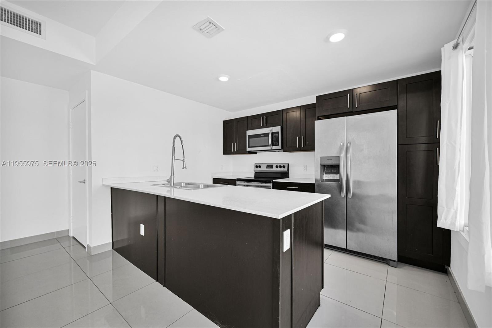 25874 Southwest 139th Court Homestead, FL 33033 - Photo 10 of 56 a kitchen with a sink a refrigerator and a microwave