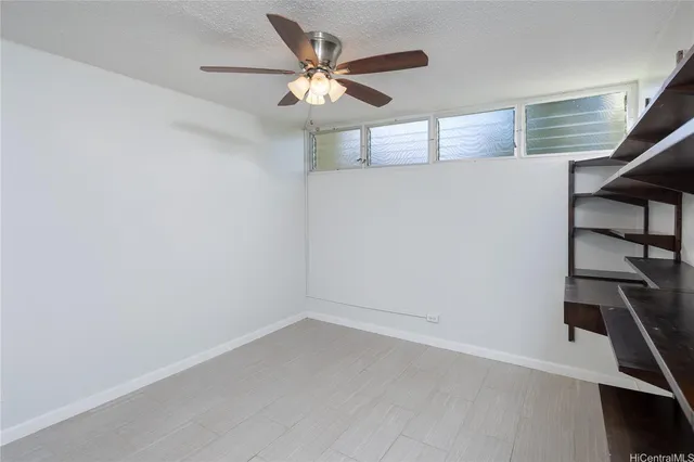 an empty room with windows and fan
