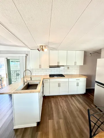 a kitchen with stainless steel appliances granite countertop a sink a stove a refrigerator cabinets and wooden floor