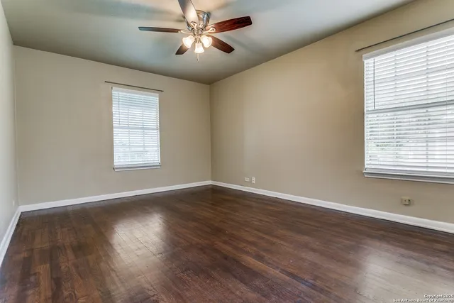 a view of empty room with wooden floor and fan