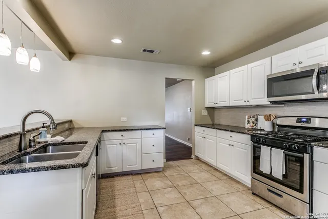 a kitchen with granite countertop a stove sink and cabinets