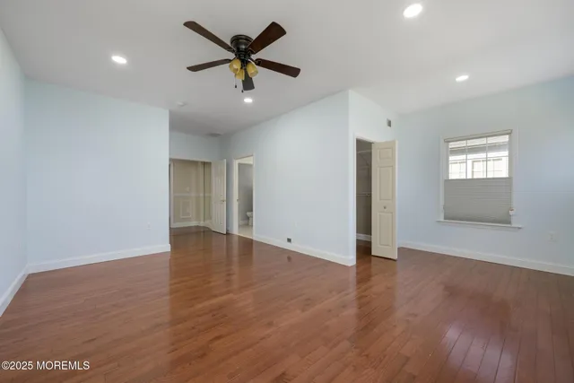 an empty room with wooden floor fan and windows