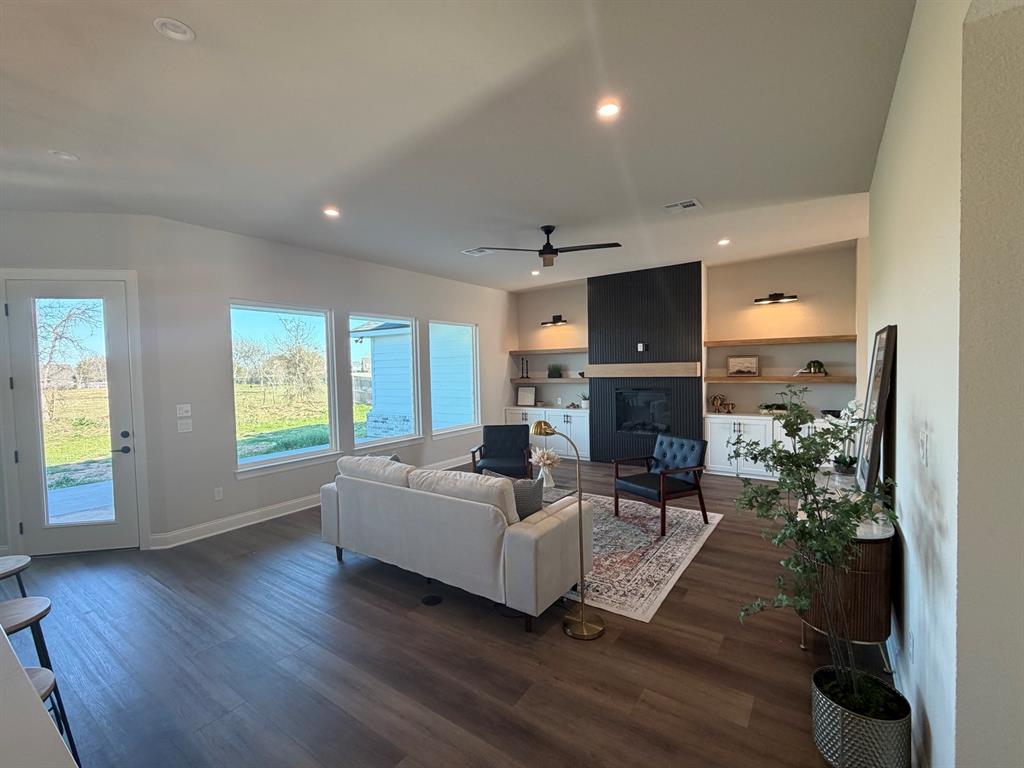 10401 T T Bury Lane Waco, TX 76708 - Photo 3 of 16 Living area with ceiling fan, a glass covered fireplace, dark wood-type flooring, recessed lighting, and vaulted ceiling