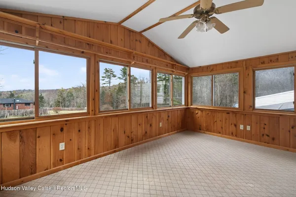 an empty room with wooden floor cabinet and windows