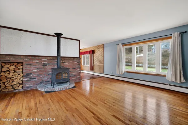 a view of an empty room with window and wooden floor