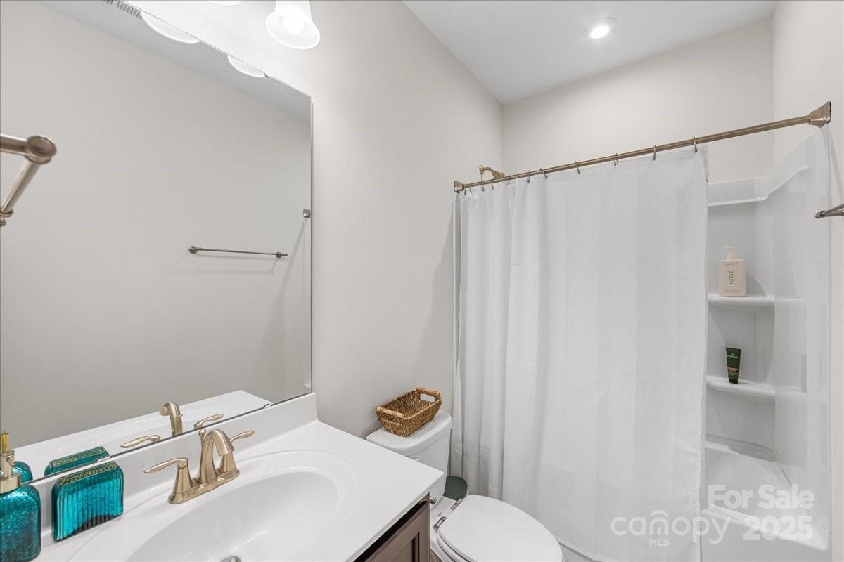 11413 Miller Road Pineville, NC 28134 - Photo 37 of 45 a bathroom with a sink a toilet a mirror and shower curtain