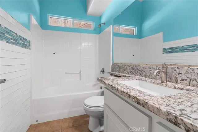 a bathroom with a granite countertop sink a toilet and bathtub
