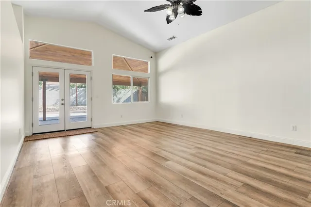 an empty room with wooden floor and windows