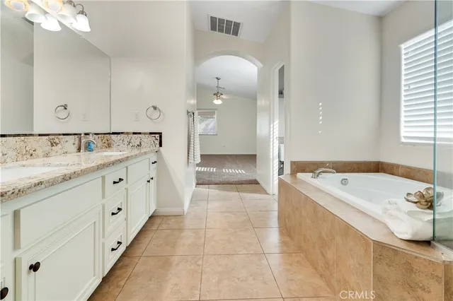 a spacious bathroom with a tub sink and mirror