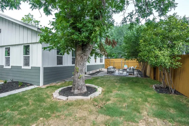 a backyard of a house with fountain plants and large tree