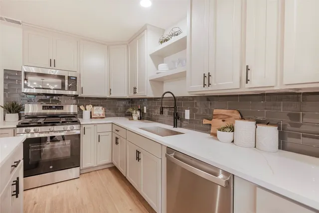 a kitchen with stainless steel appliances granite countertop a sink a stove and cabinets