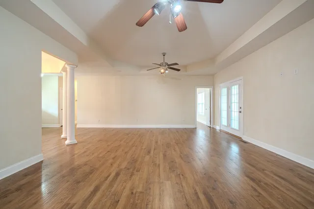 a view of an empty room with a window and wooden floor