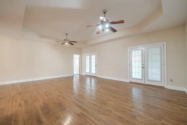 a view of an empty room with a chandelier fan and wooden floor