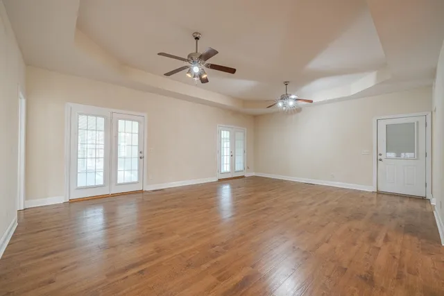 a view of an empty room with a window and wooden floor