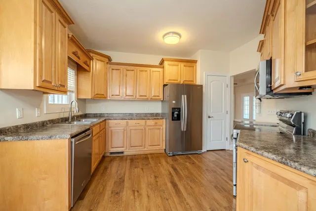 a kitchen with stainless steel appliances granite countertop a refrigerator a stove and a sink with cabinets